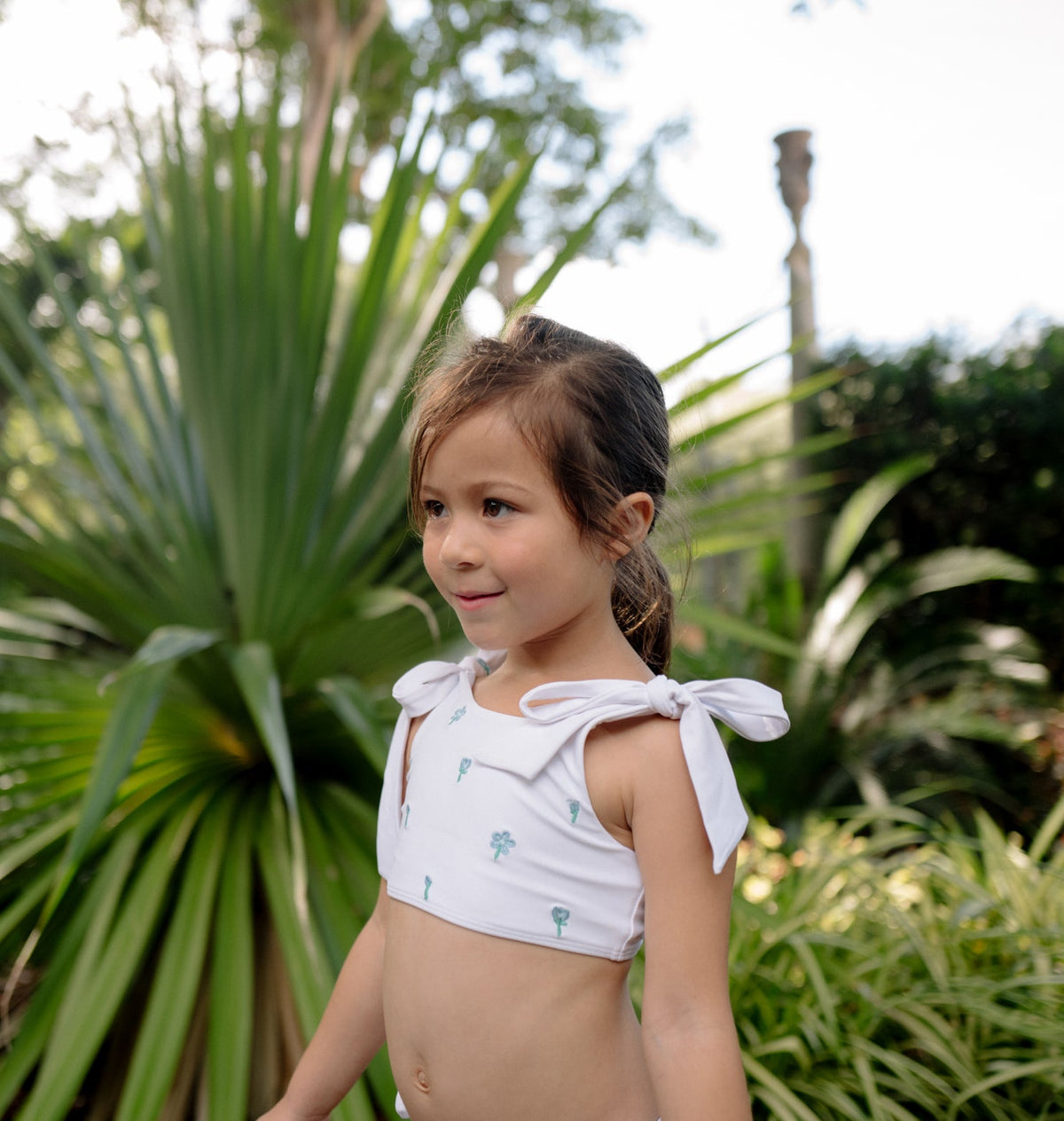 Three quarter view of Girls Coconut Grove White Tie Knot Bikini on a child showing shoulder ties and hibiscus details