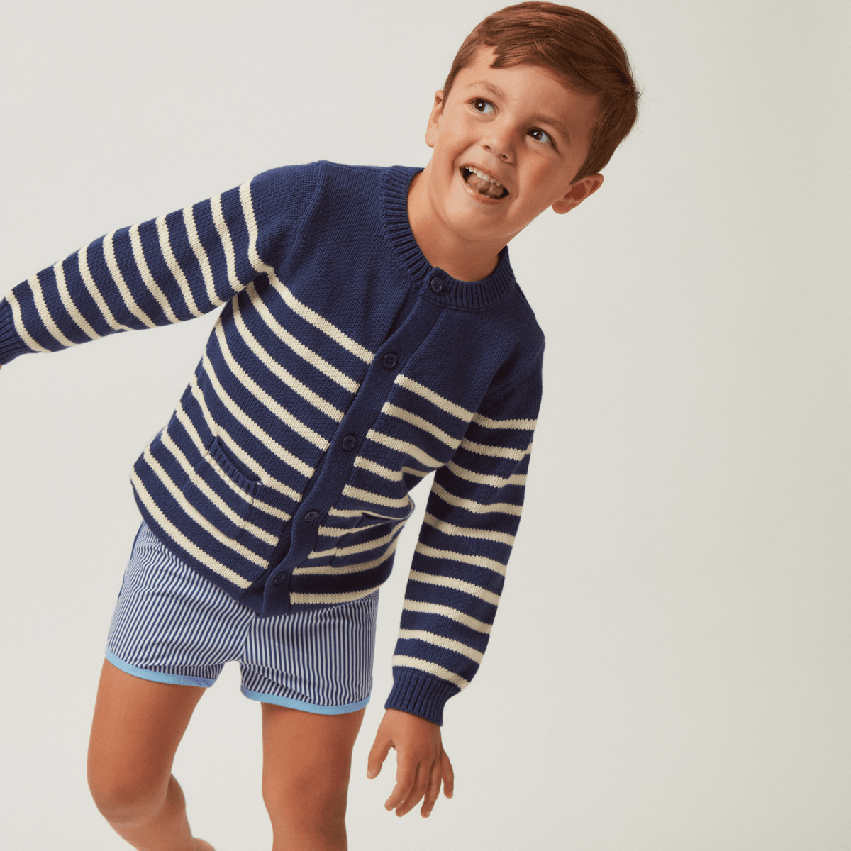 Three-quarter view of boys stripe boardie in navy and white with light-blue trim worn by child on plain background