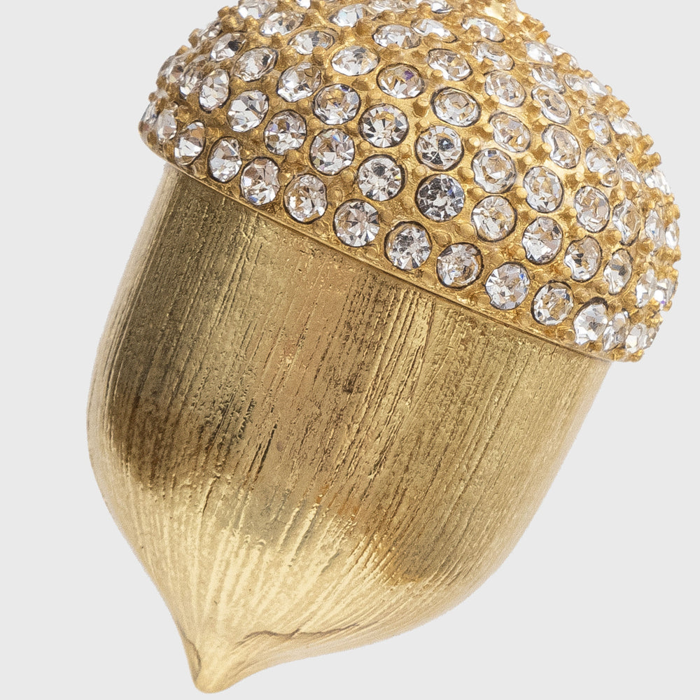 Close-up of acorn hanging ornament showcasing gold-tone textured body and crystal-studded cap on light gray background