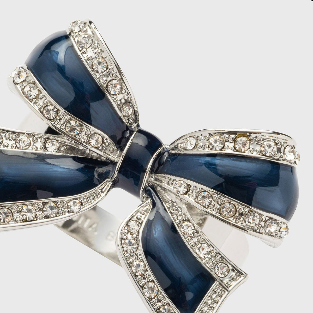 Close-up of enamel bow skinny napkin ring in navy showcasing rhinestone-trimmed silver edges on light gray background