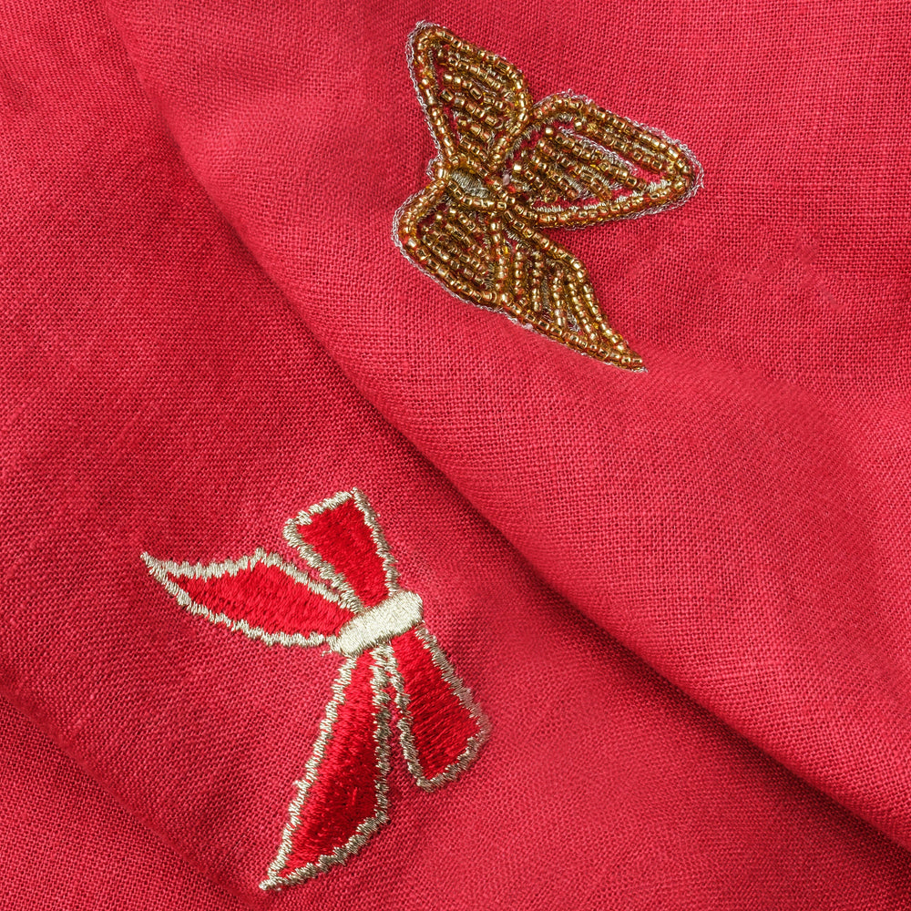 Close-up of Bow Extra Large table runner showing red linen with embroidered bows and a gold-beaded bow