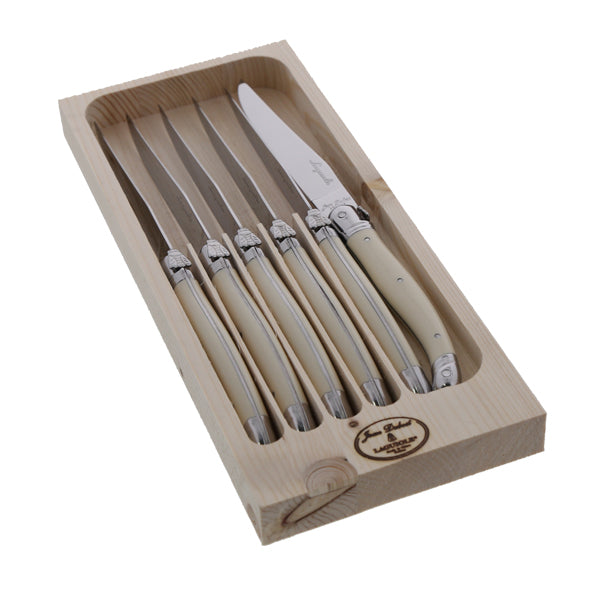 Angled view of six ivory-handled Laguiole steak knives in wooden tray showcasing polished stainless steel blades on white background