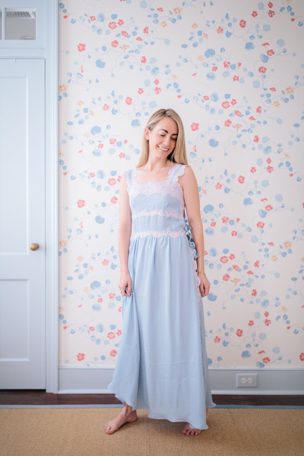 Full-length view of Sabina Silk Nightgown, light blue on model, showing lace-trimmed bodice, spaghetti straps and side ribbon ties
