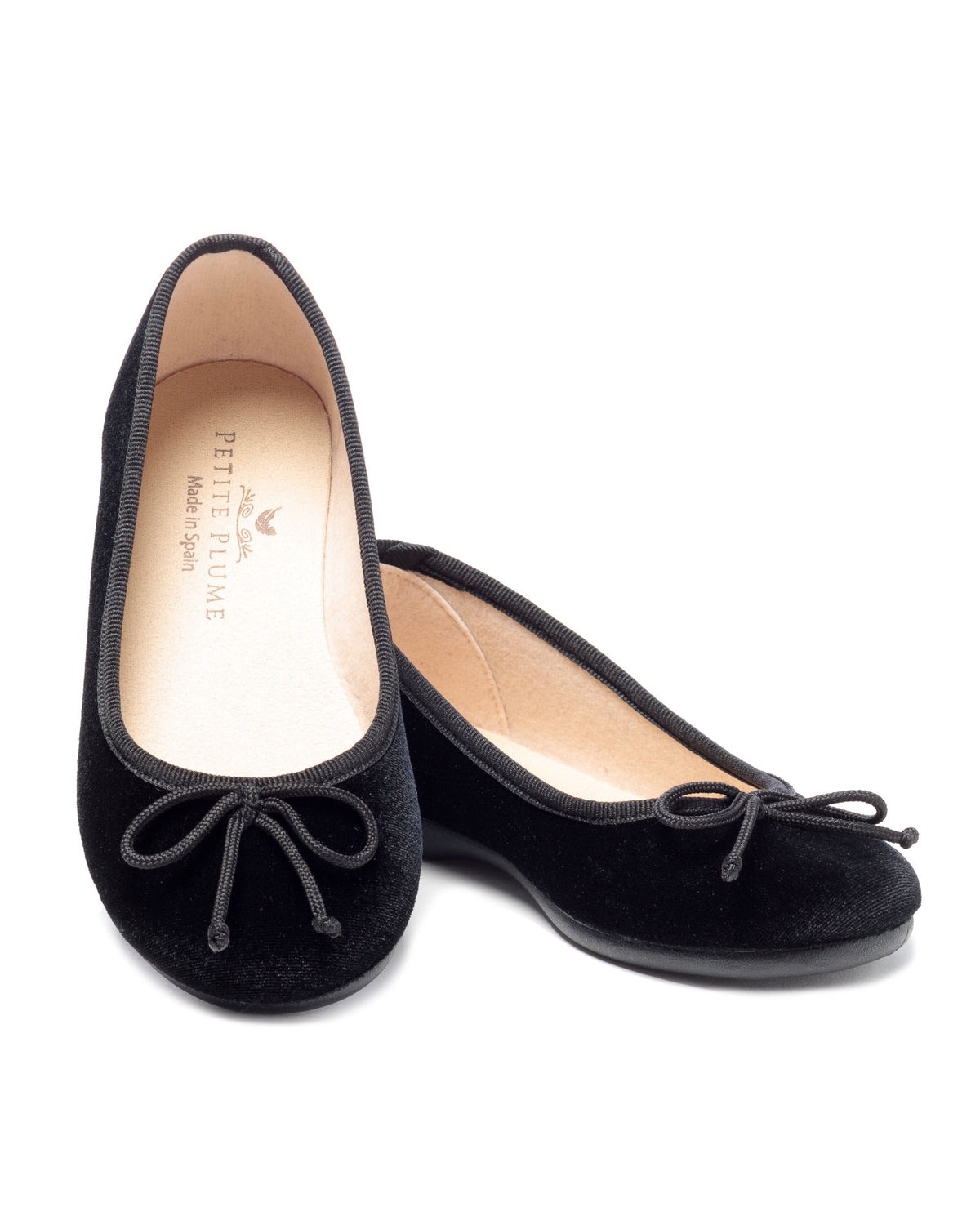 Angled view of Juliette ballet slippers in black velvet showcasing bow details and soft insoles on a white background