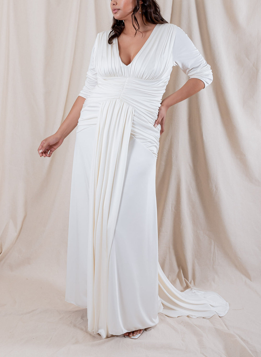 Front view of Nicole Silk Ruched Gown showing ruched bodice, V-neckline, and draped front train on beige backdrop