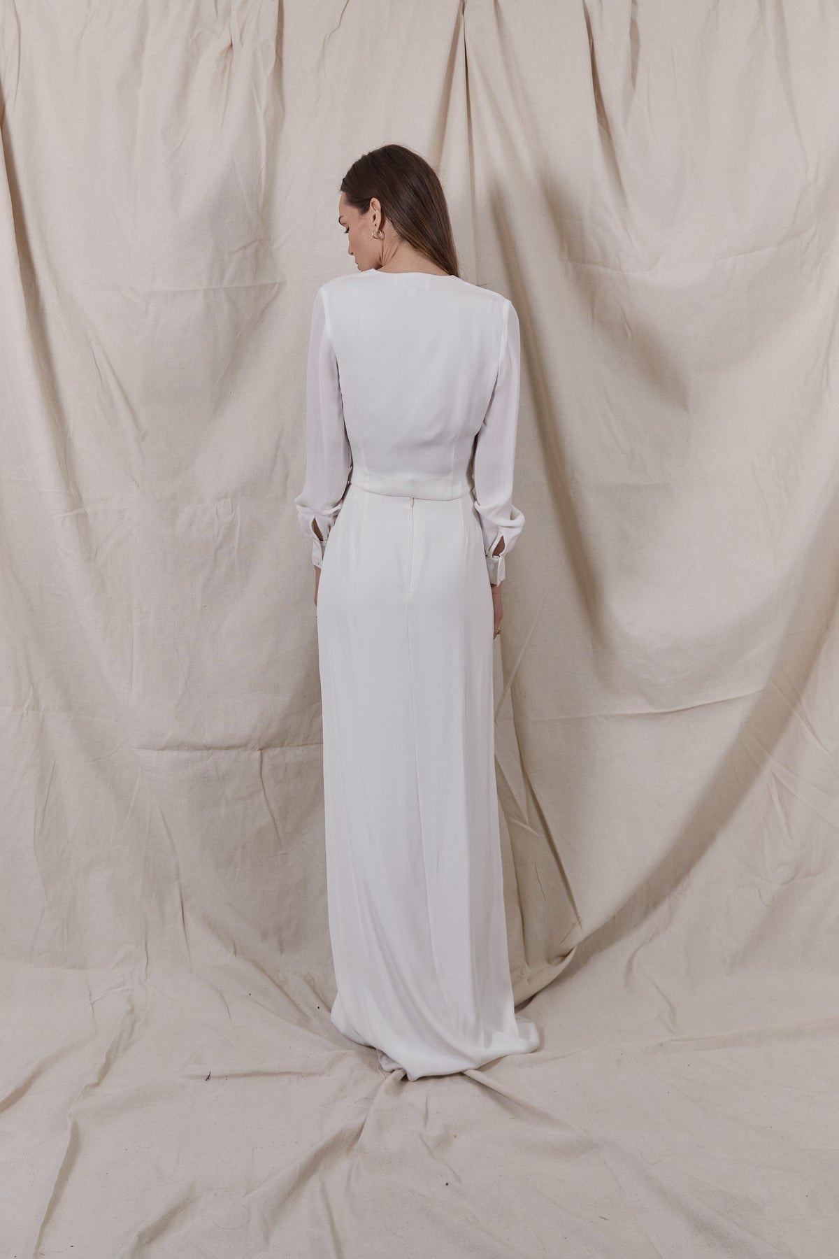Back view of Soraya Silk Skirt showcasing high waist and floor-length drape with beige fabric backdrop