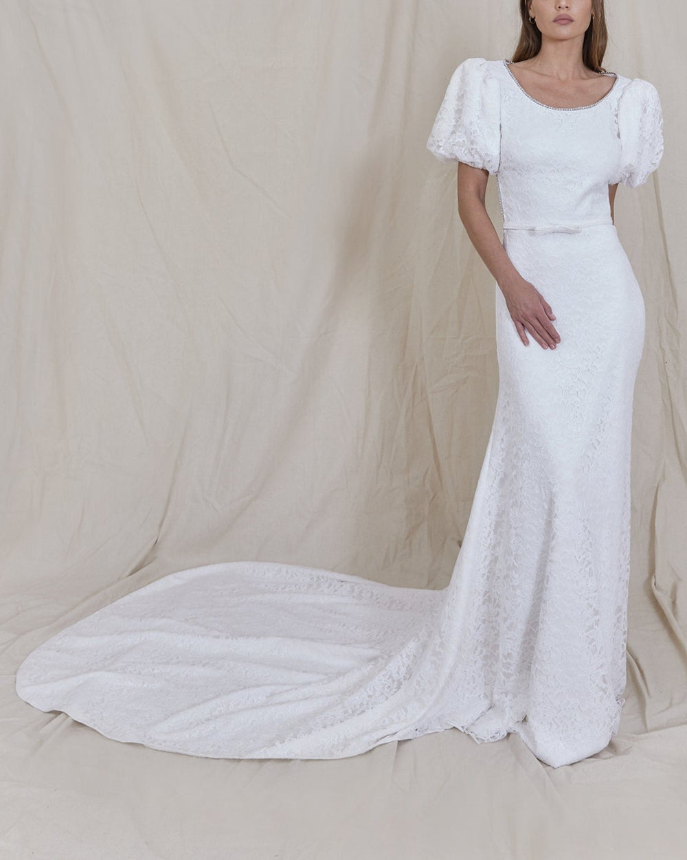 Front view of Gwen Gown in Lace with puff sleeves, crystal-trimmed neckline, bow belt and long lace train