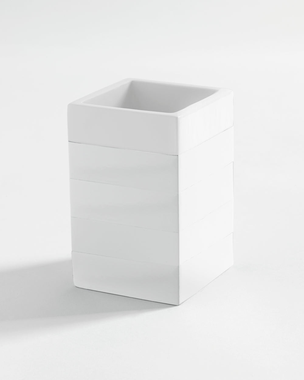 Angled view of Cabana Solid bath tumbler showing square shape, glossy lacquered resin and horizontal banding on white