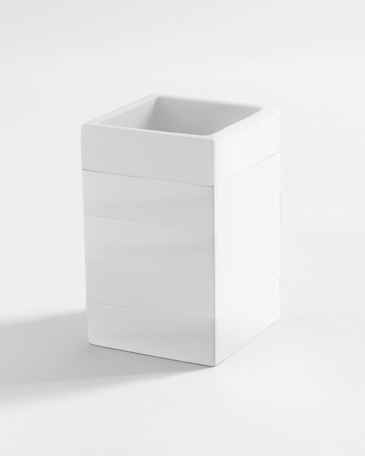 Angled view of Cabana Solid bath tumbler showing square shape, glossy lacquered resin and horizontal banding on white