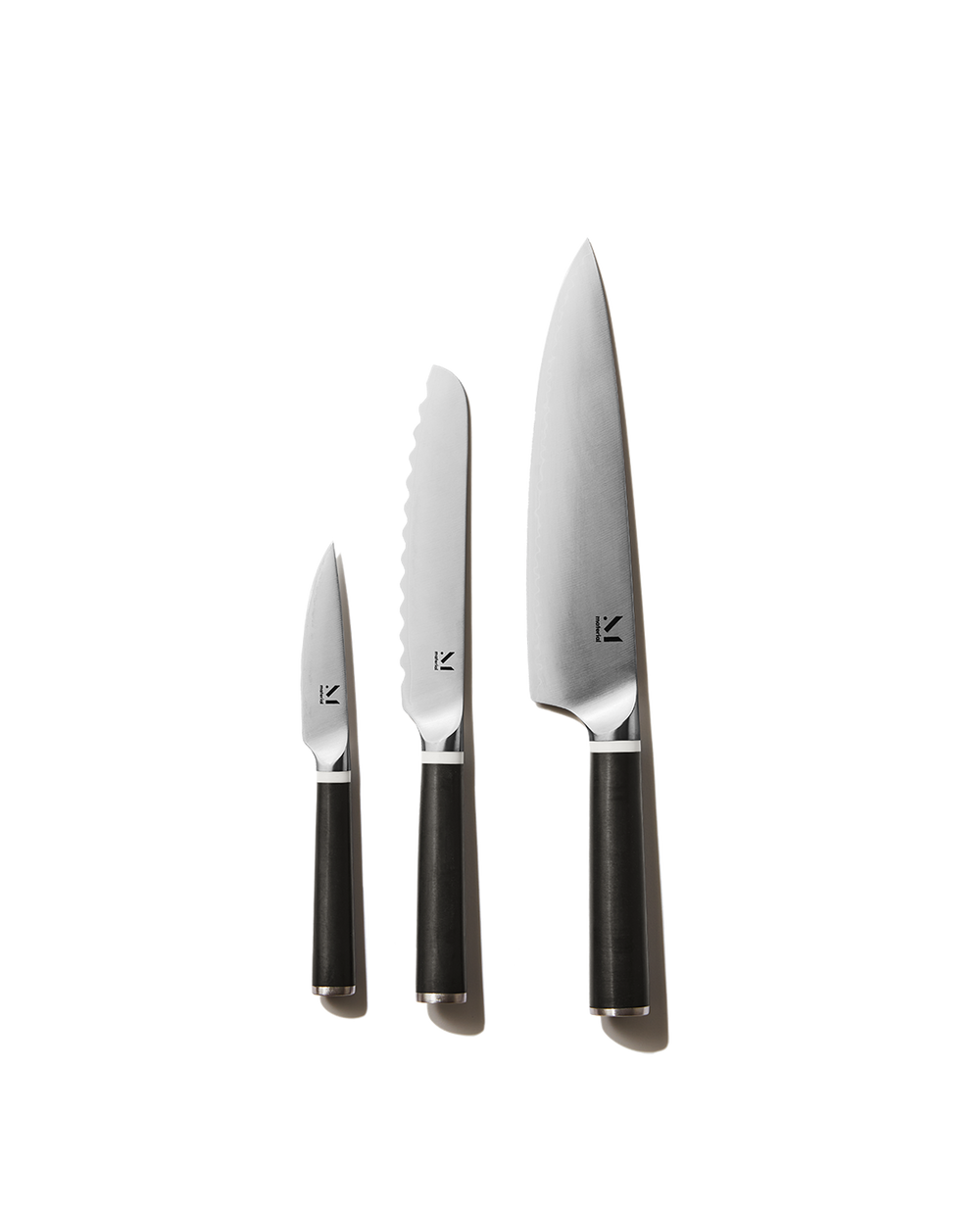 Front view of three-piece knife set (chef knife, serrated knife, paring knife) with black handles on white background