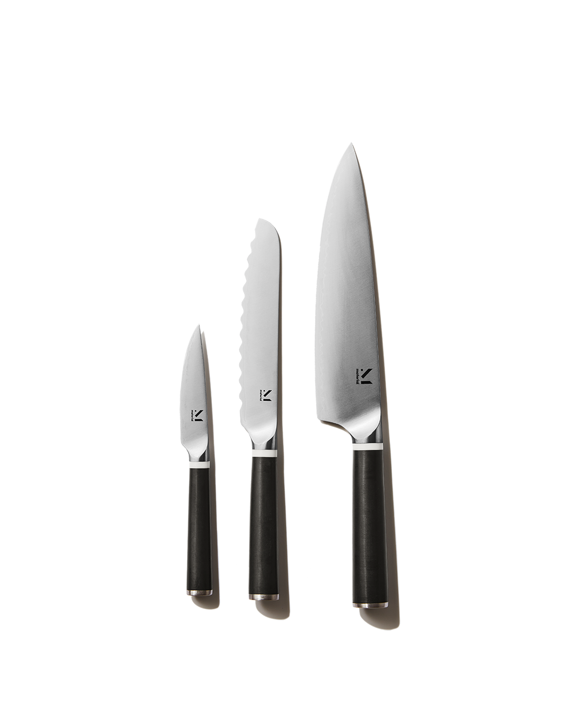 Front view of three-piece knife set (chef knife, serrated knife, paring knife) with black handles on white background