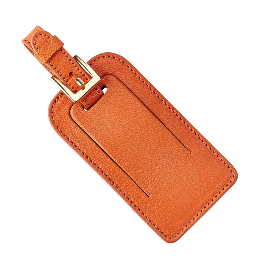 Angled top-down view of orange goatskin leather luggage tag showcasing gold buckle strap and stitched edges on white background