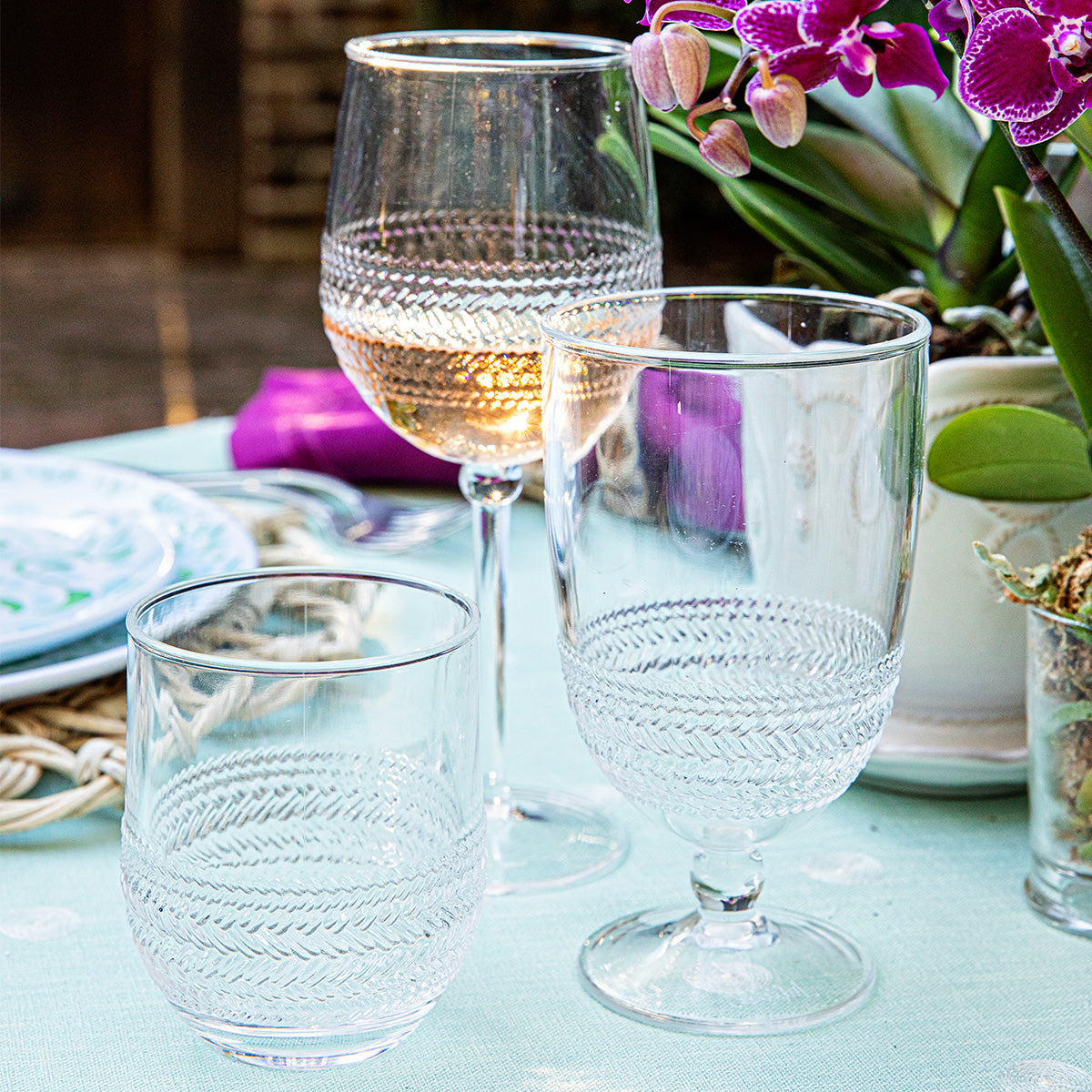 Front view of Le Panier Clear Acrylic Wine Glass showcasing textured basket-weave bands with a floral table setting