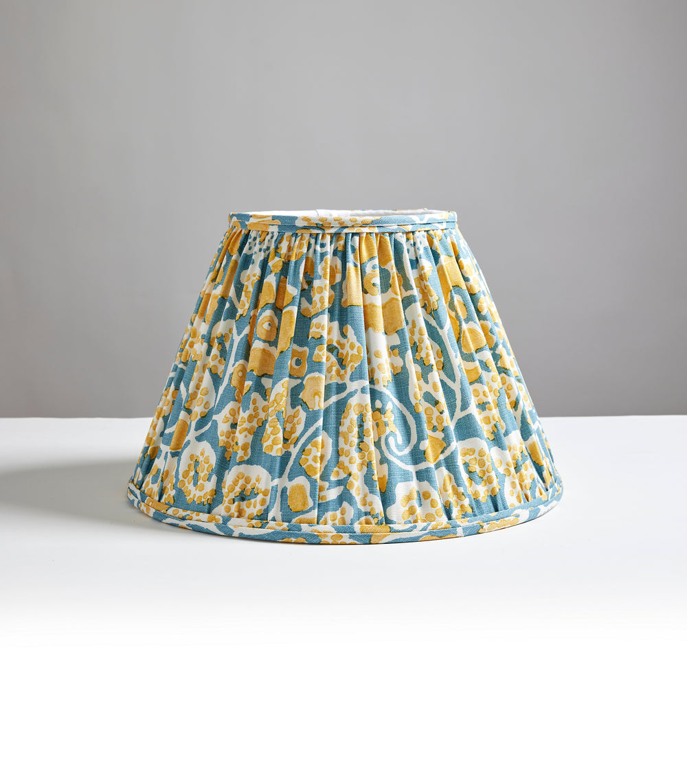 Front view of Maiden Floral Pleated Shade showing pleated Aruba Denim floral fabric on a white tabletop