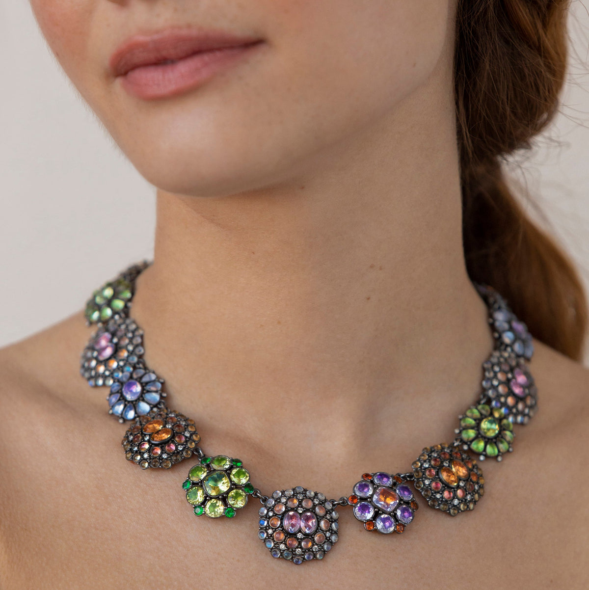 Close-up view of Luzia Royal Cluster Rivière showcasing multicolored gemstones on a model’s neck