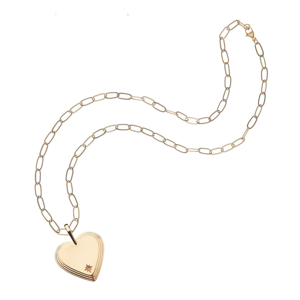 Top view of Layers Of Love heart necklace showing layered heart pendant with starburst engraving on gold paperclip chain