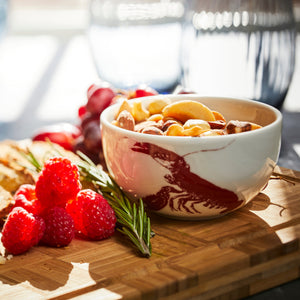 A Red Lobster Snack Bowl from Caskata holds nuts on a wooden charcuterie board.