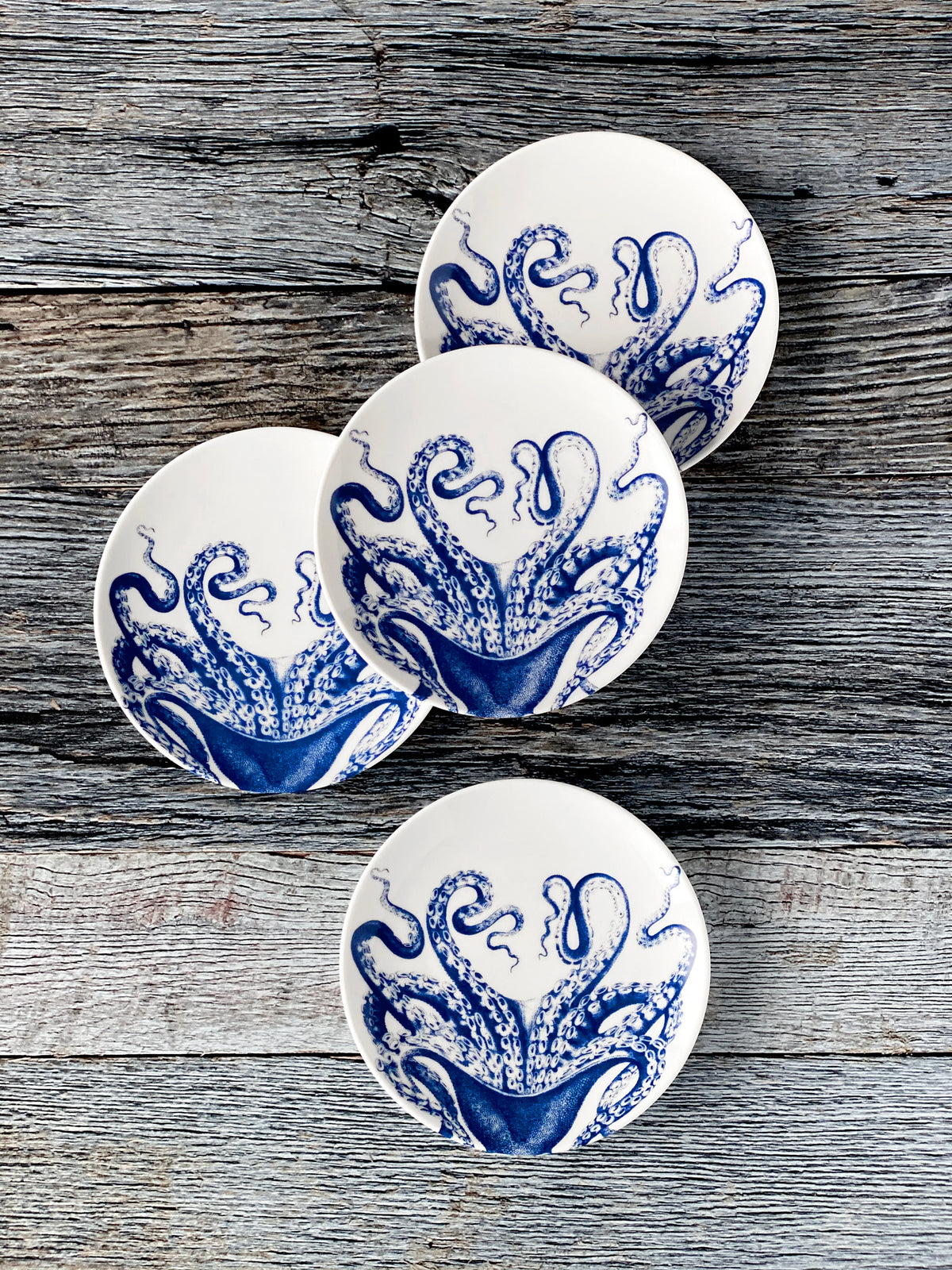 Overhead view of Lucy Dipping Dish, Set of 4 showcasing blue cephalopod designs on bone china with a wood background