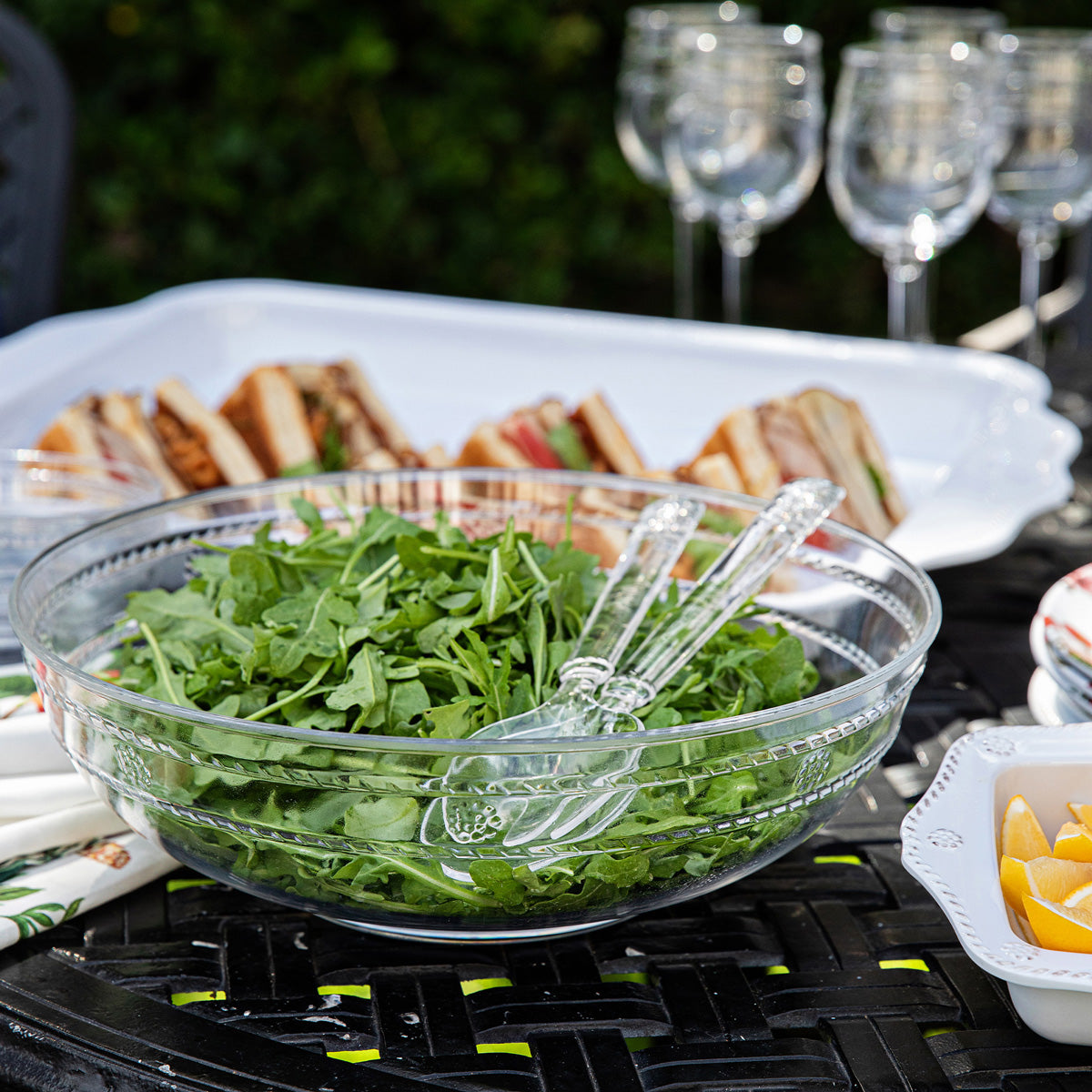 Close-up of Isabella Arcylic Salad Servers showcasing decorative handle details with a salad bowl on an outdoor table