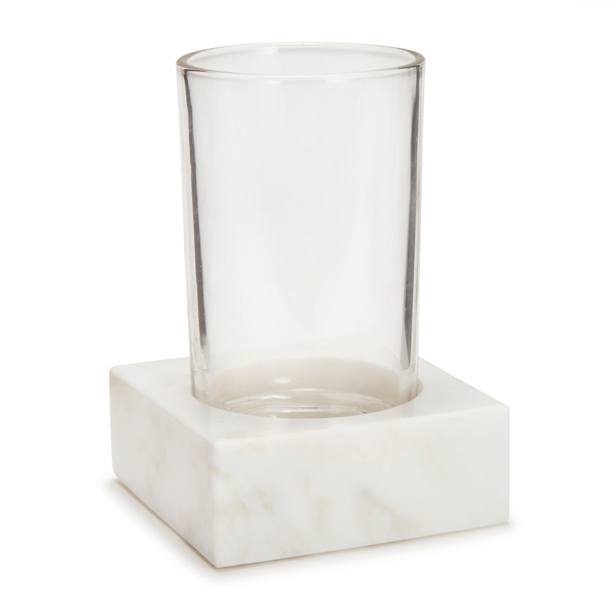 Angled front view of Marmol Bath Tumbler showing a clear glass cup set in a square white marble base on white background