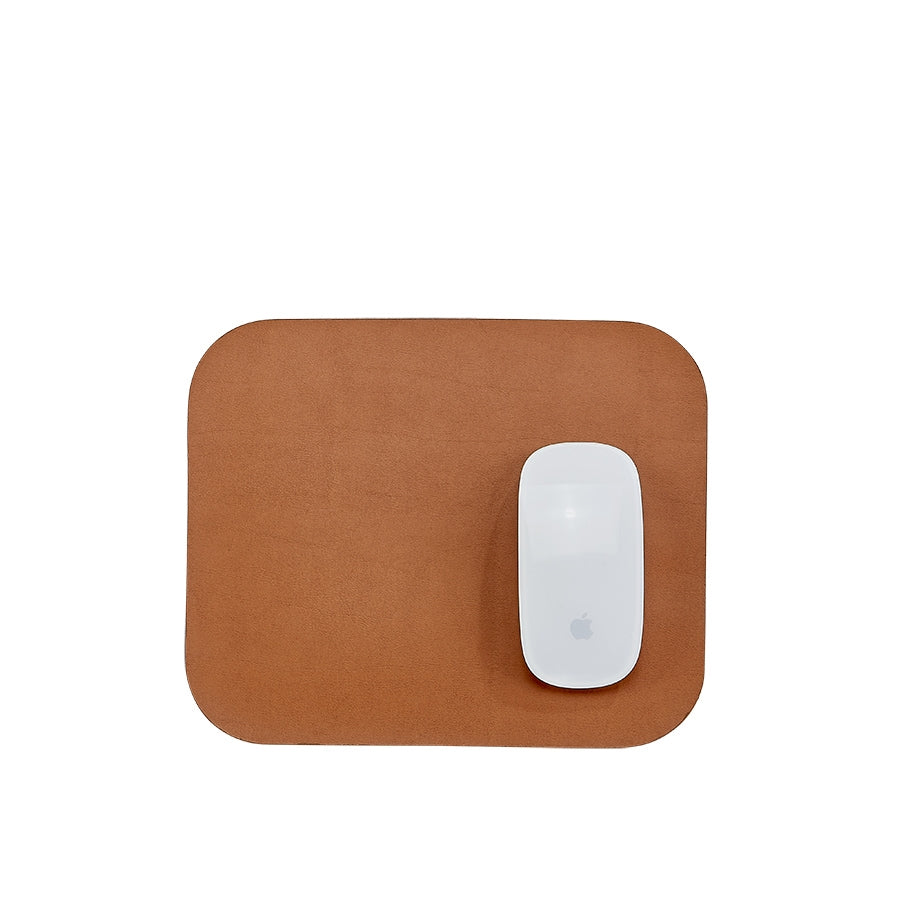 Top view of Italian leather mouse pad in tan with rounded corners and white wireless mouse on white background