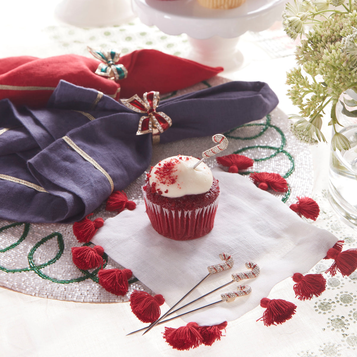 Overhead view of Candy Cane Cocktail Picks showcasing jeweled candy cane tops with a festive cupcake and holiday table setting