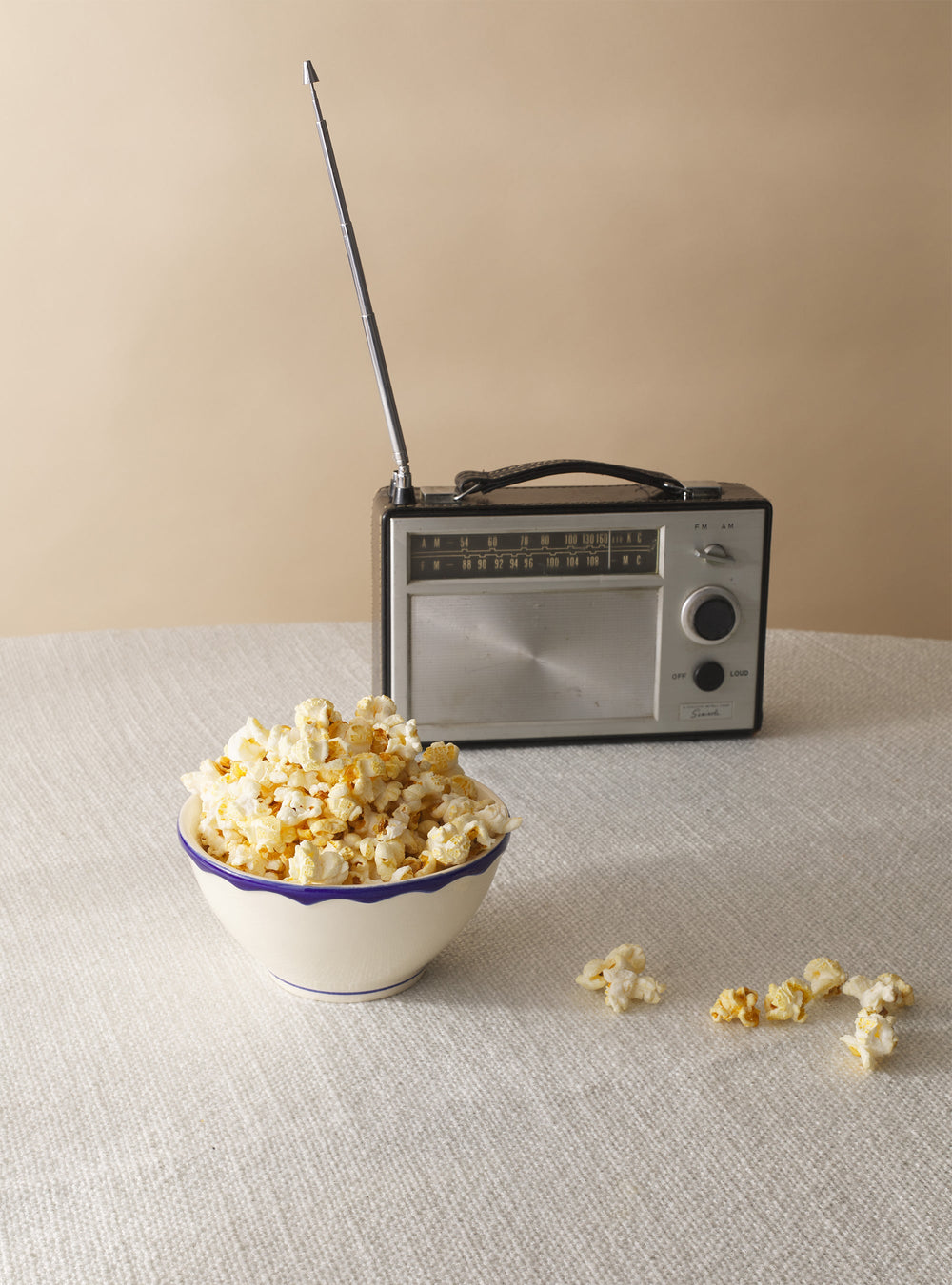 Front view of Maison Madison cereal bowl with scalloped sea-blue rim, filled with popcorn on a beige tablecloth