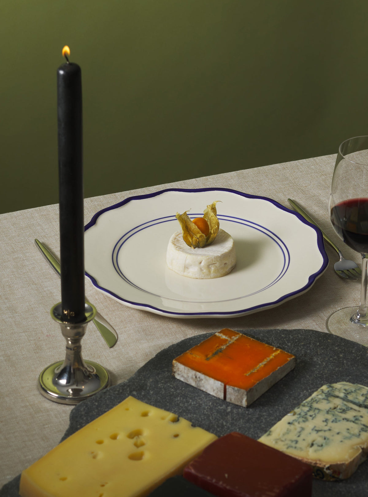 Angled top view of Jane dinner plate showcasing scalloped sea-blue rim and double blue inner rings on a linen table