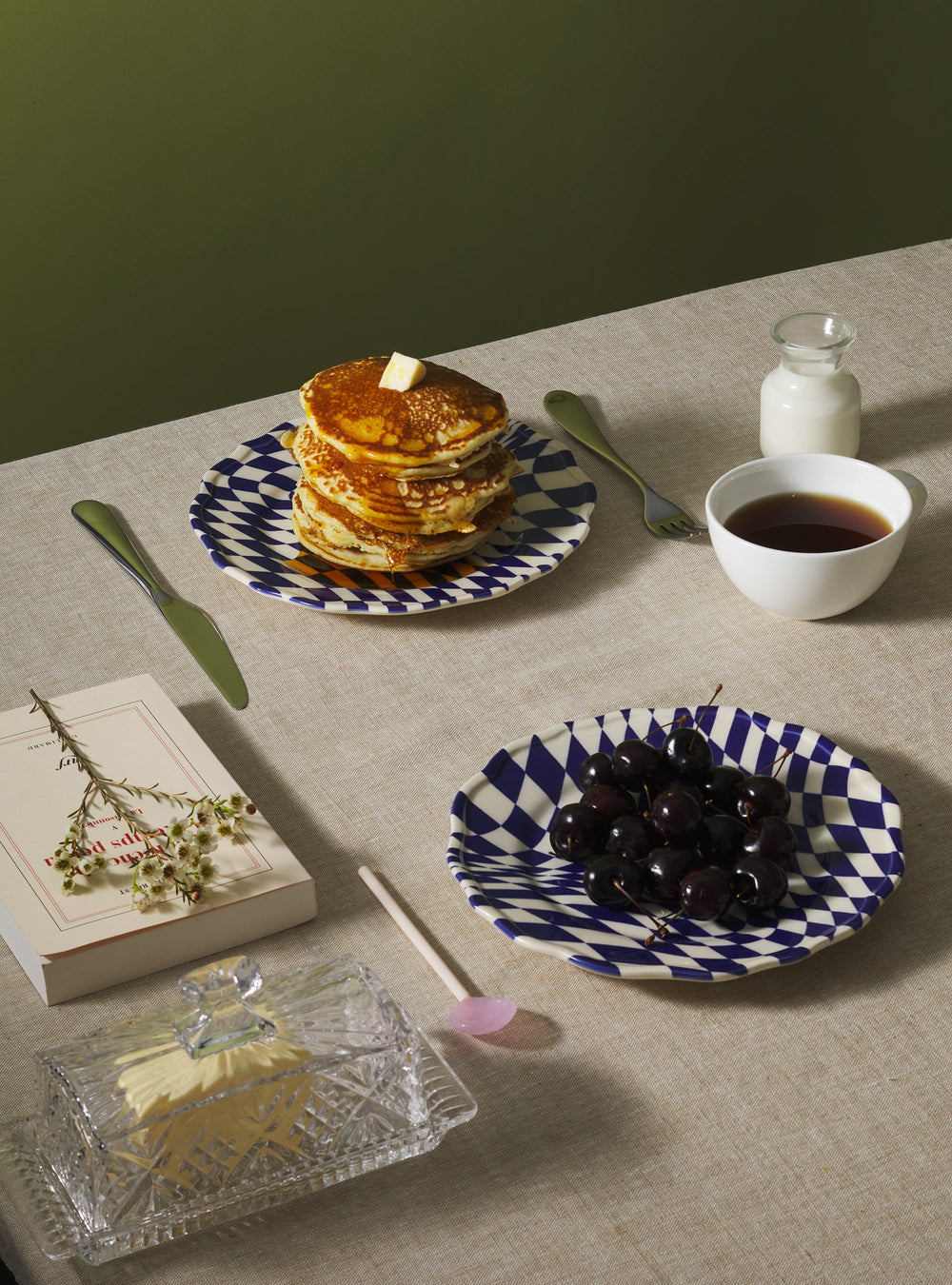 Mafalda dessert plate with blue pattern holding pancakes on a linen table with matching cherries plate and cup of tea