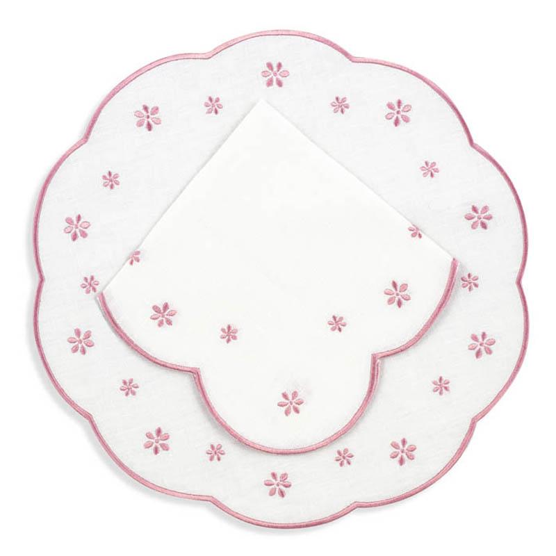 Top down view of Margueritte round linen placemat and scalloped napkin with pink floral embroidery on white background