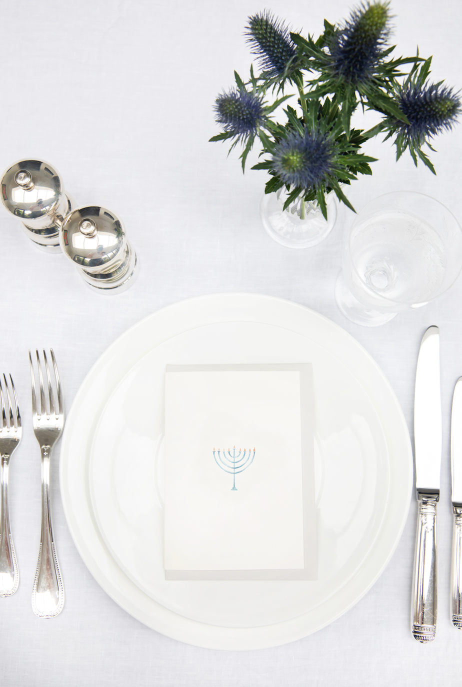 Top view of Hanukkah card showcasing a watercolor menorah illustration on a table setting