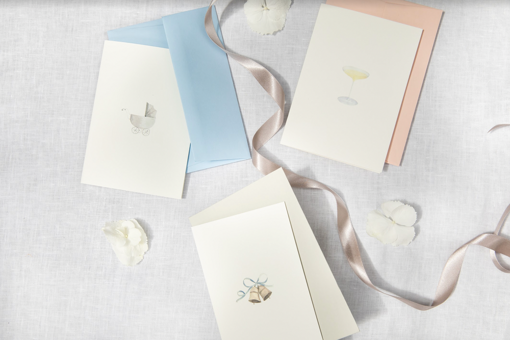 Top-down view of Wedding Bells card showing watercolor bells illustration with envelope on linen background