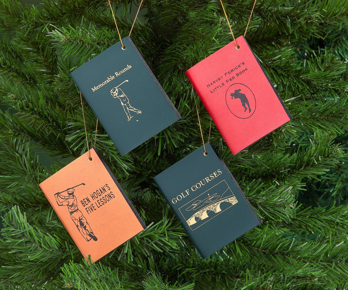 Front view of Mini Leather Ornaments: The Golfer showcasing embossed golf designs on four leather ornaments with an evergreen tree background