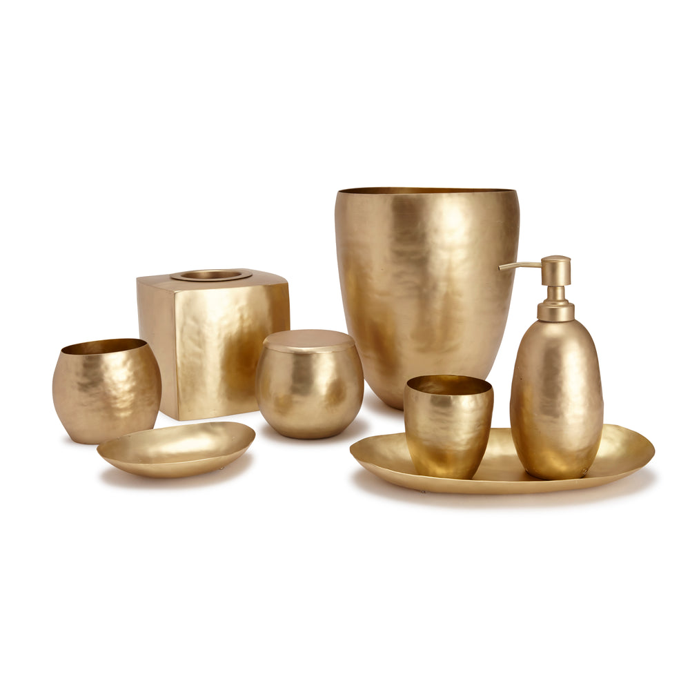 Front view of Nile bath lotion dispenser in hammered gold brass finish with matching bathroom accessory set on white background