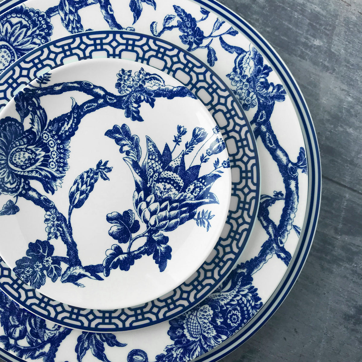 Top view of Newport Blue Charger Plate showcasing geometric blue border with layered floral dinnerware background