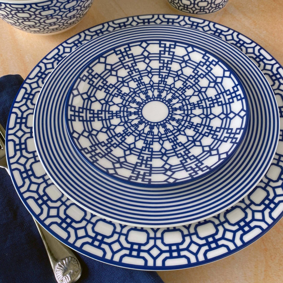 Overhead view of Newport Canapé Plates Boxed, Set of 4 showcasing blue geometric patterns on creamy white porcelain