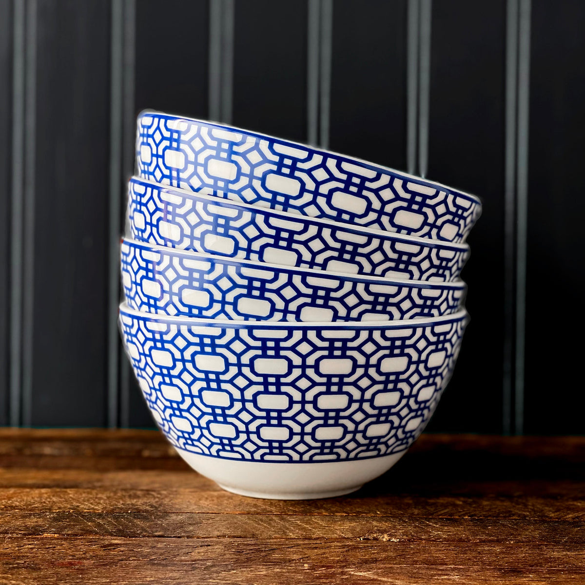 Front view of Newport Tall Cereal Bowl showcasing blue geometric pattern on creamy white porcelain with a dark background
