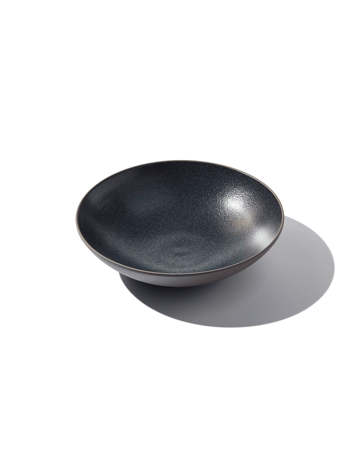 Three-quarter view of The Open Bowl showcasing its hand-finished Korean clay surface on a green background