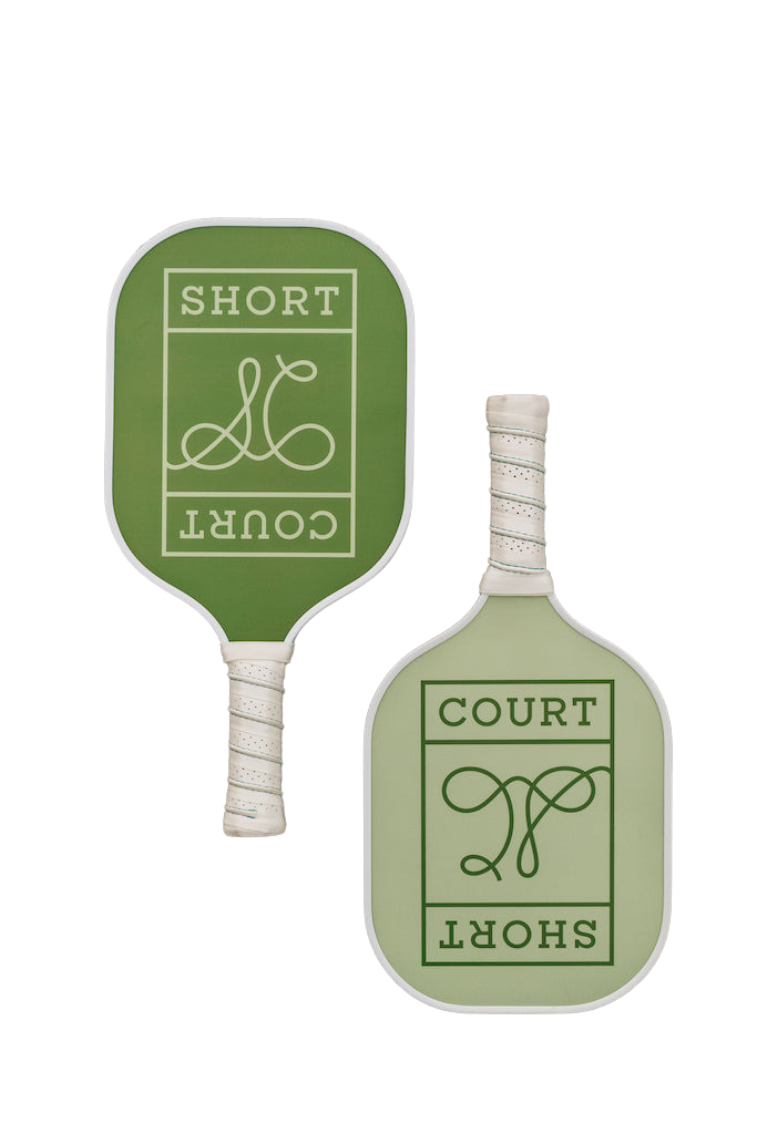 Flat lay of pickleball paddles by Short Court showing mint and grass green faces, white wrapped grips, and logo on black background