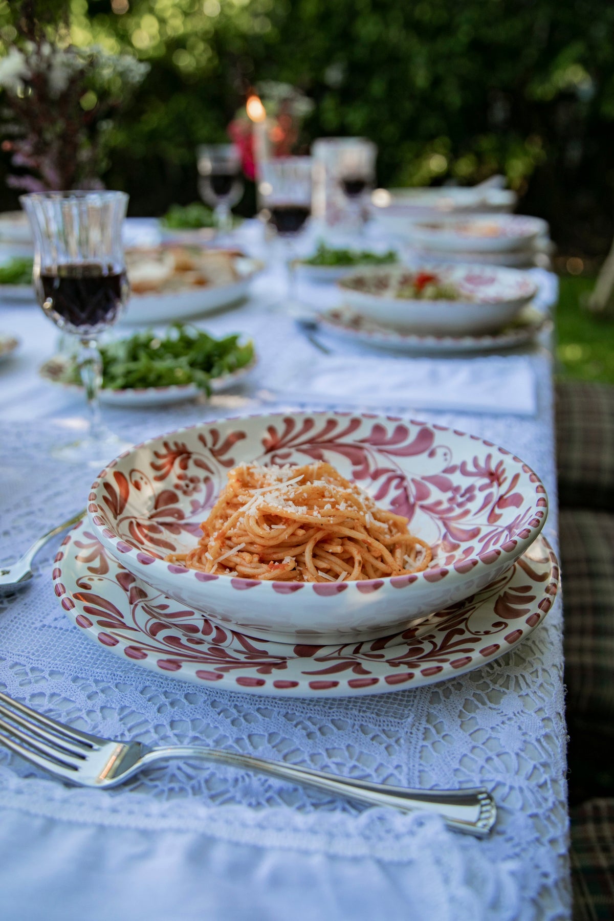 Deep Pasta Plate holds spaghetti at an outdoor table with leafy patterns and candlelight