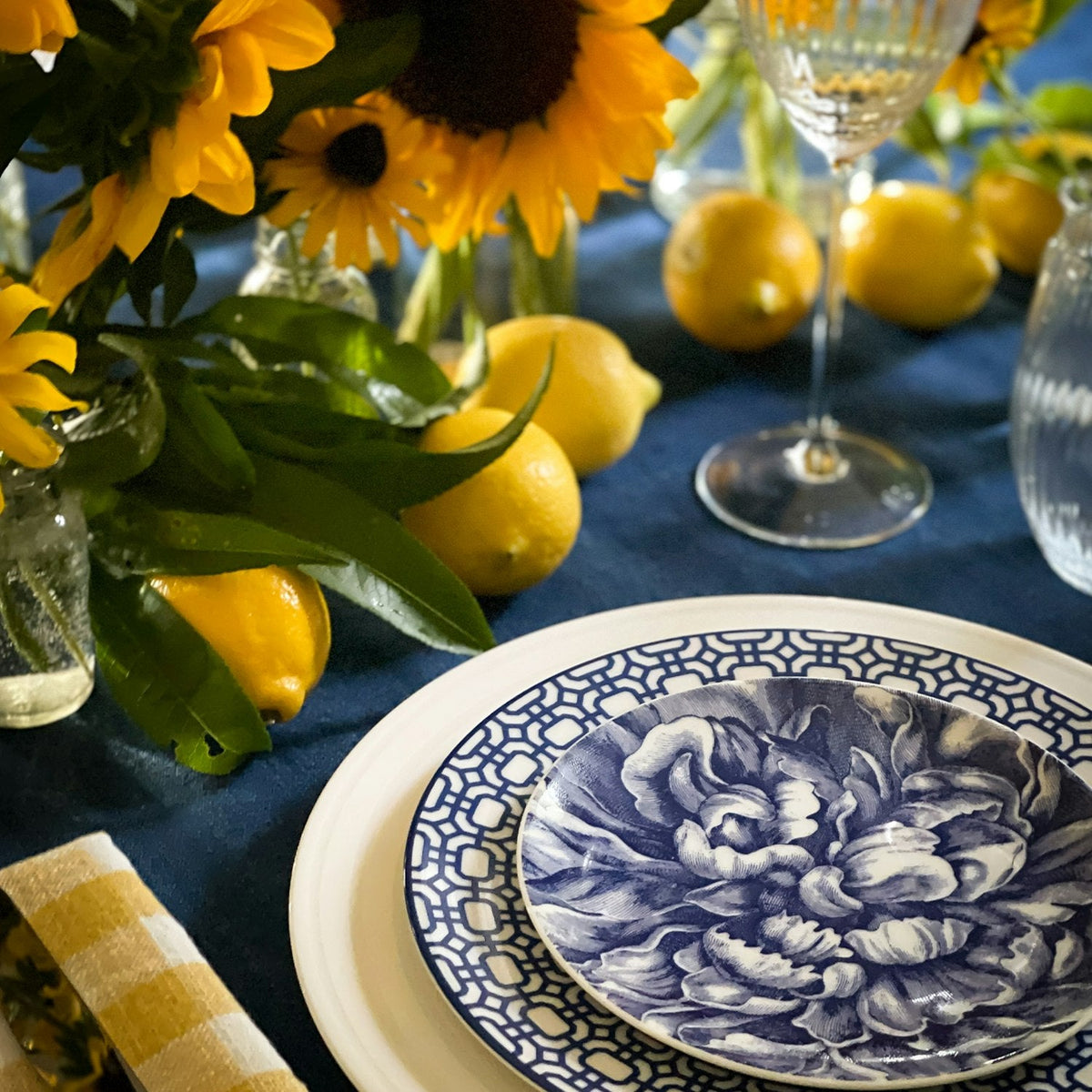 A high-fired porcelain table setting with sunflowers and lemons, featuring Caskata Artisanal Home's Peony Canapé Plates.