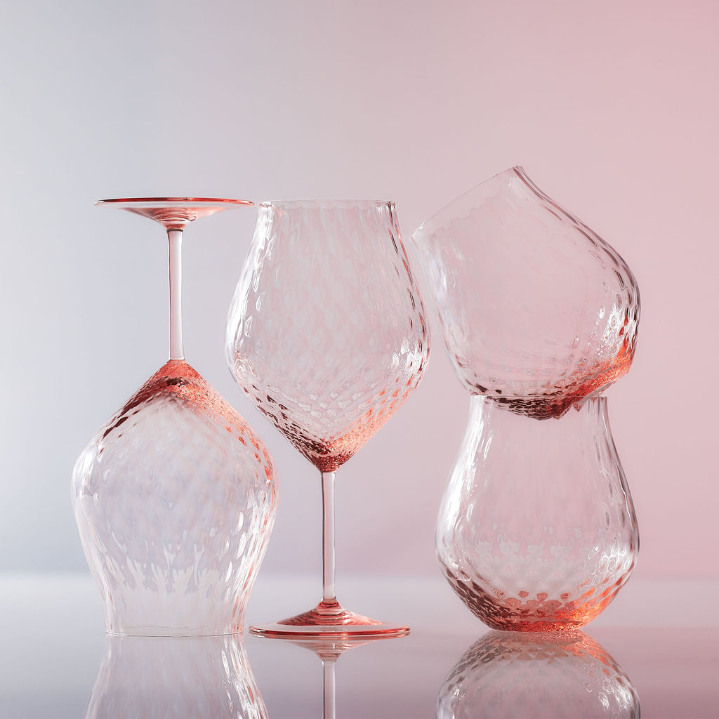 Phoebe rose pink universal and stemless tulip crystal wine glasses from Caskata on a pink backdrop.