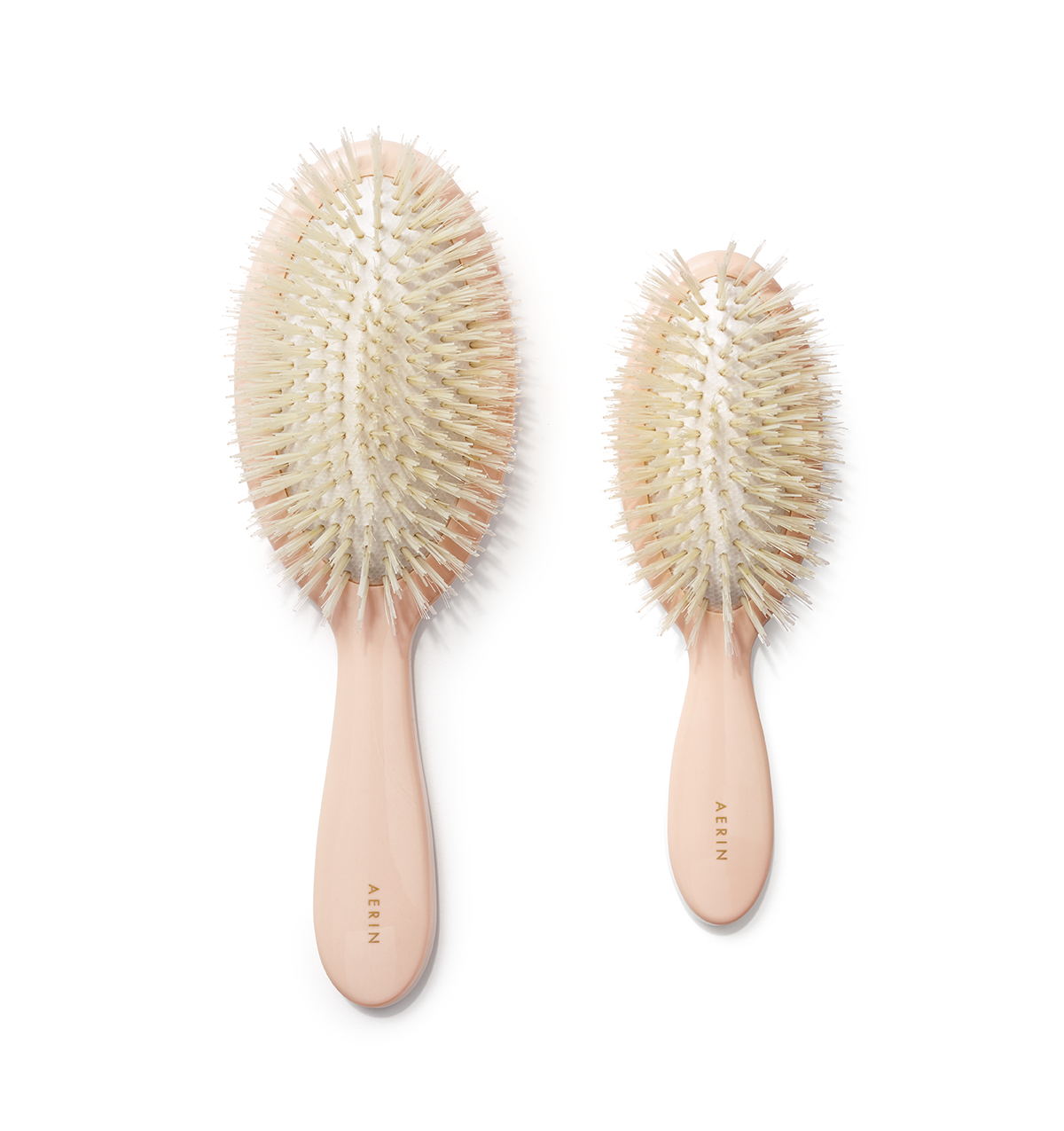 Top-down view of large and small pink pastel hair brushes showcasing boar and nylon bristles and acrylic handles on white background