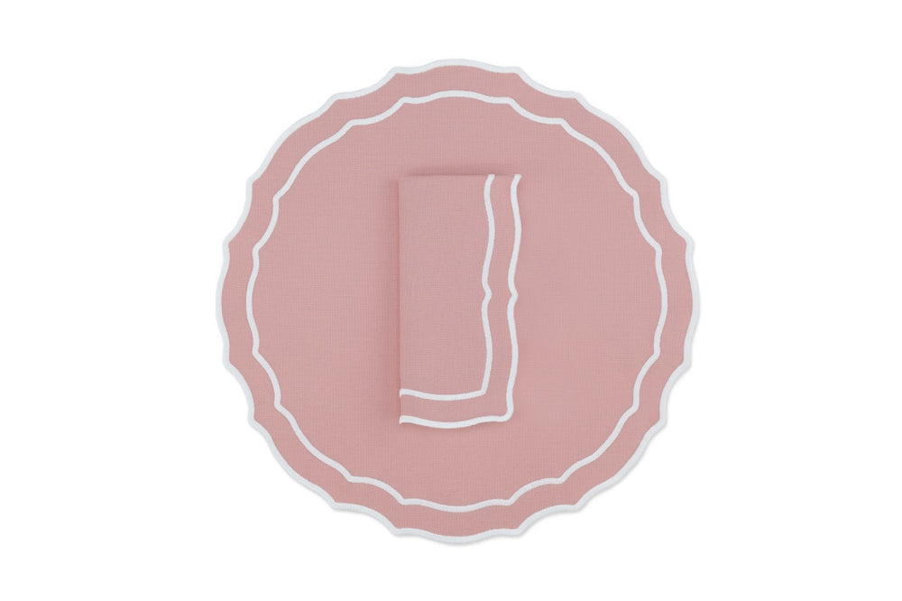 Top view of Vidro cotton-blend placemat and folded napkin set of four in dusty pink showing scalloped edge and white trim on white background