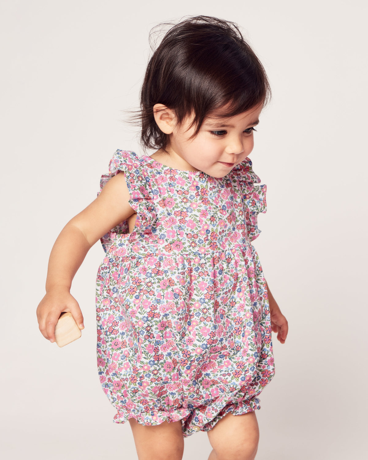 Three-quarter view of Children’s Fleurs de Rose Ruffled Romper with pink floral print and ruffled sleeves