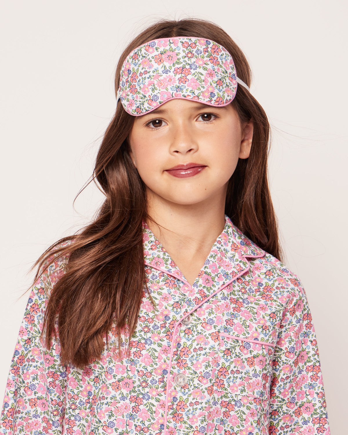 Front view of Children’s Fleurs de Rose Sleep Mask showcasing pink floral print, worn on a child with matching pajamas