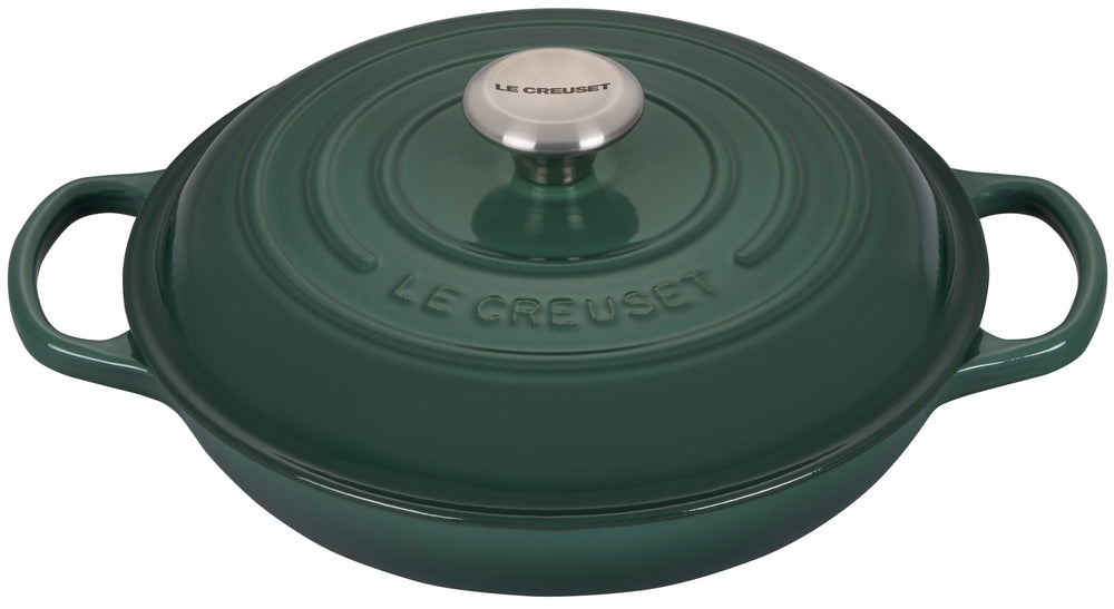 Top view of Le Creuset Signature Braiser in artichaut green with domed lid, stainless steel knob, and loop handles on white background
