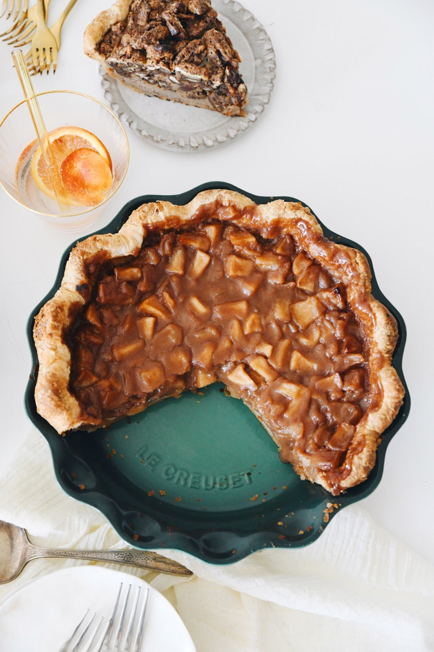 Top view of 9 inch Heritage pie dish in deep teal showing scalloped rim and embossed Le Creuset logo with apple pie