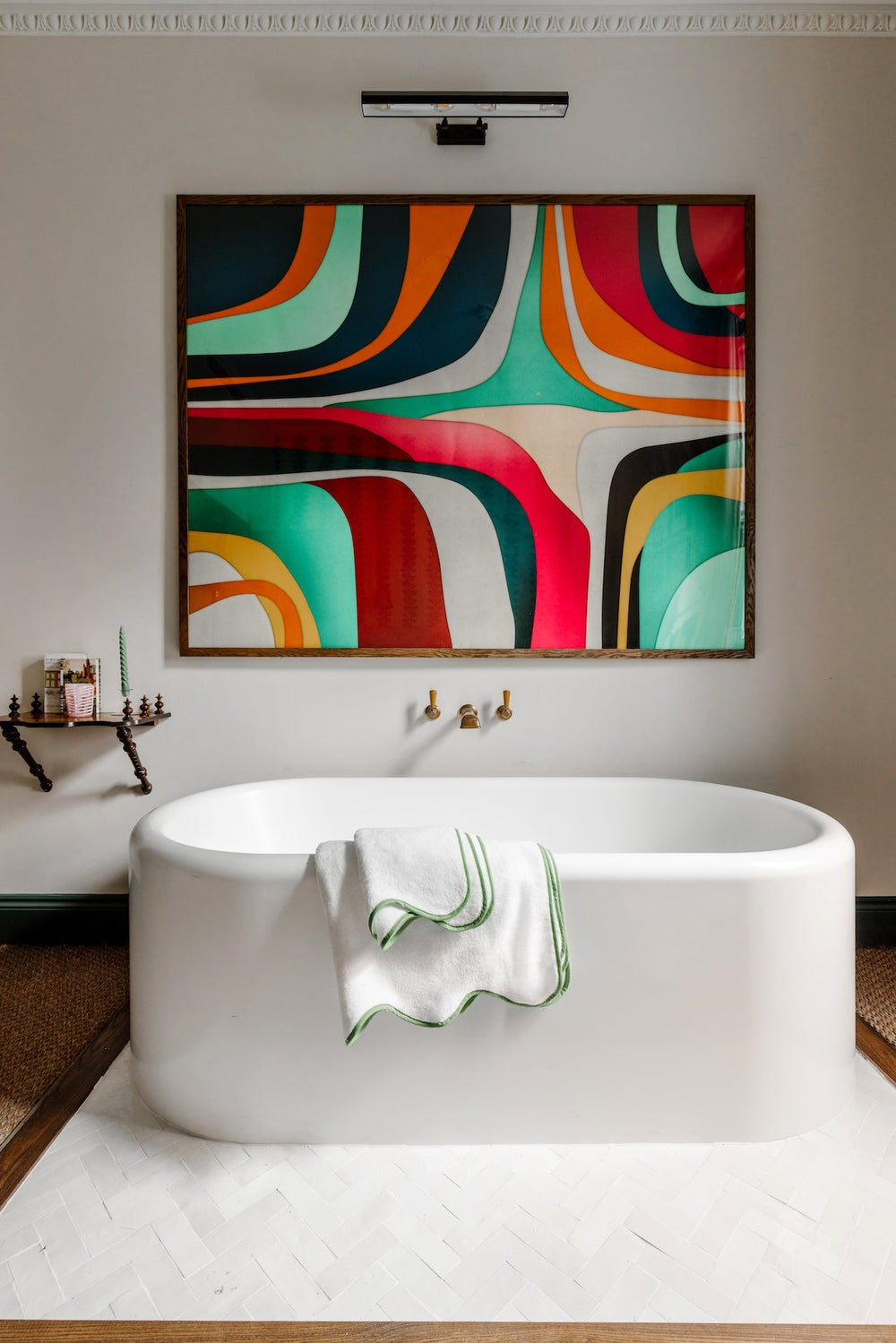 Front of Amelia Scalloped bath towel showing green scalloped trim draped over a white freestanding tub with colorful wall art