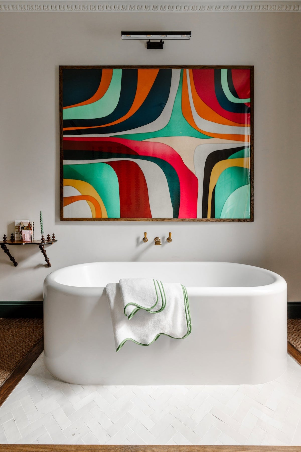 Front of Amelia Scalloped bath towel showing green scalloped trim draped over a white freestanding tub with colorful wall art